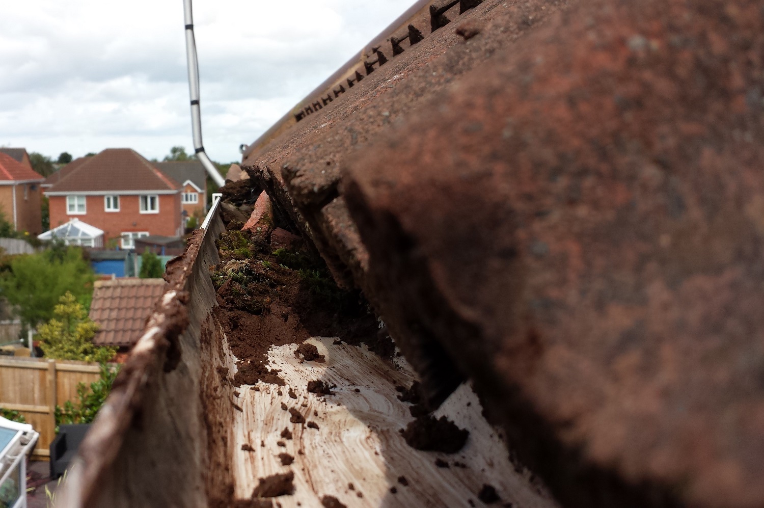 image of a blocked gutter full of sand and debris