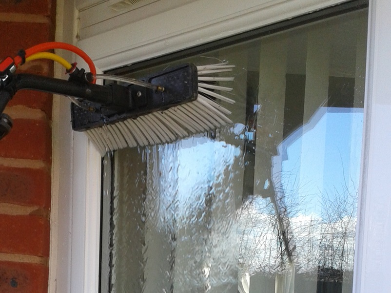 image of a window cleaning brush and running water cleaning a window